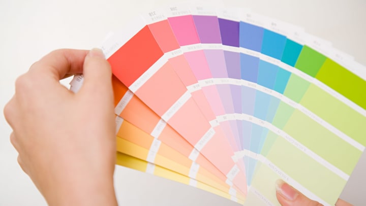 Woman’s hands holding a fan of bright color swatches.