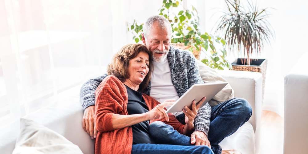 Happy couple checking iPad at Rose Cove Apartment Homes in Farmington, Utah