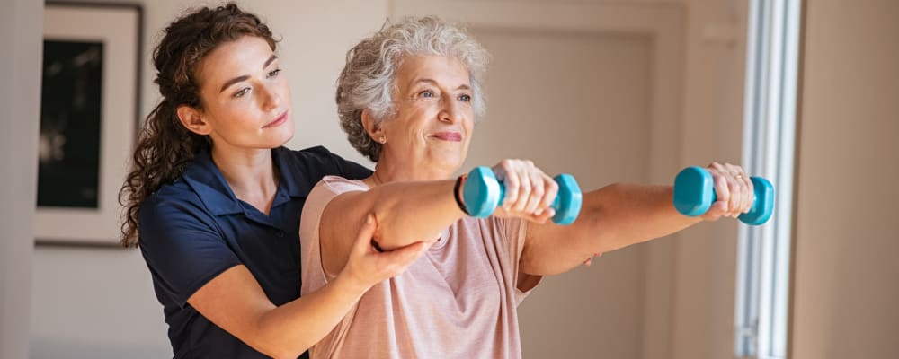 A staff member helping a resident preform exercises at Ridgeline Management Company in Rockwall, Texas