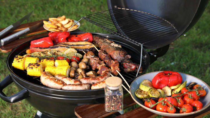 A fully loaded barbecue grill with kebabs, corn, sausages, and veggies at one of the San Antonio parks with grilling areas