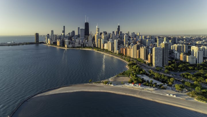 An aerial view of the downtown Chicago skyline, with a park and beach in the foreground. 