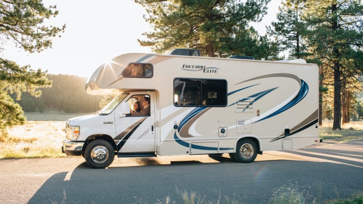 RV driven in a forest next to lake | Unsplash