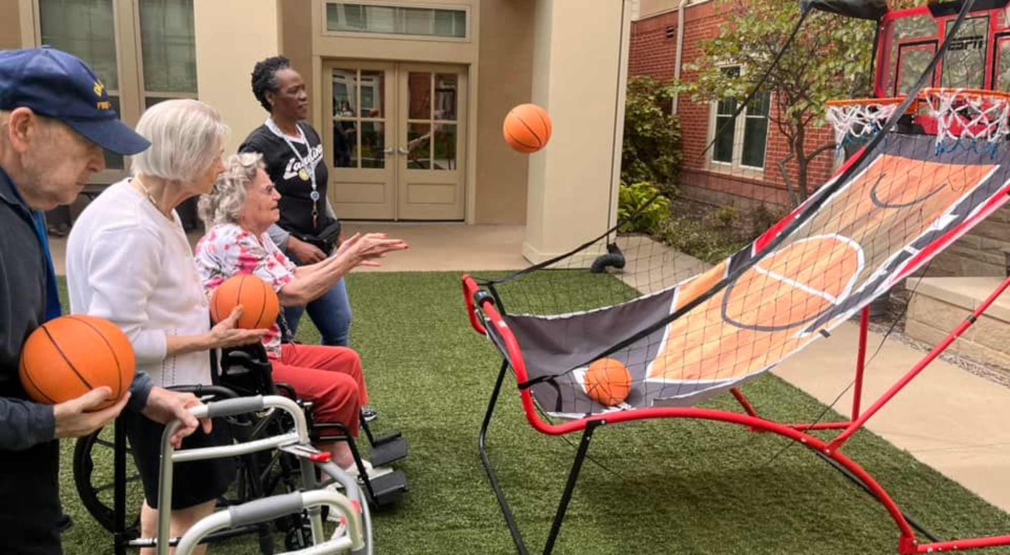 Seniors enjoying a fun game of basketball in the courtyard with support from staff.