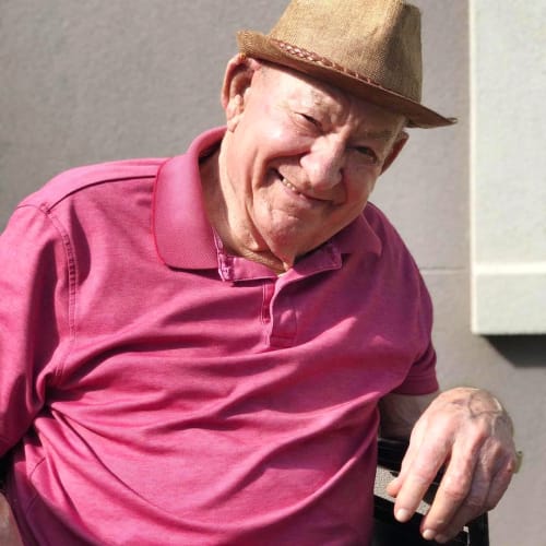 Resident sitting in a wheelchair outside in the warm sun at Oxford Glen Memory Care at Sachse in Sachse, Texas