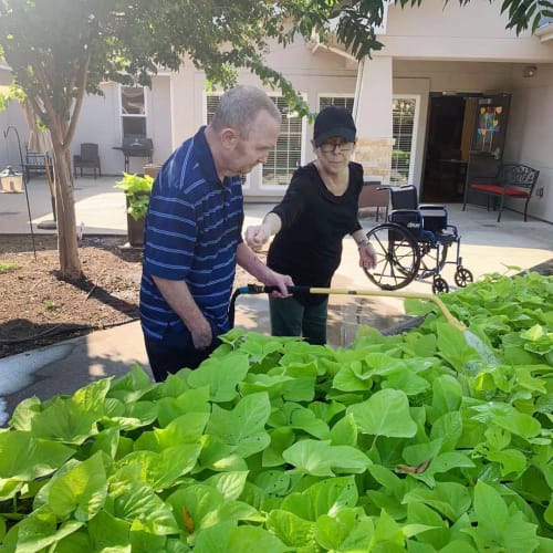 Resident couple outside watering plants at Oxford Glen Memory Care at Sachse in Sachse, Texas