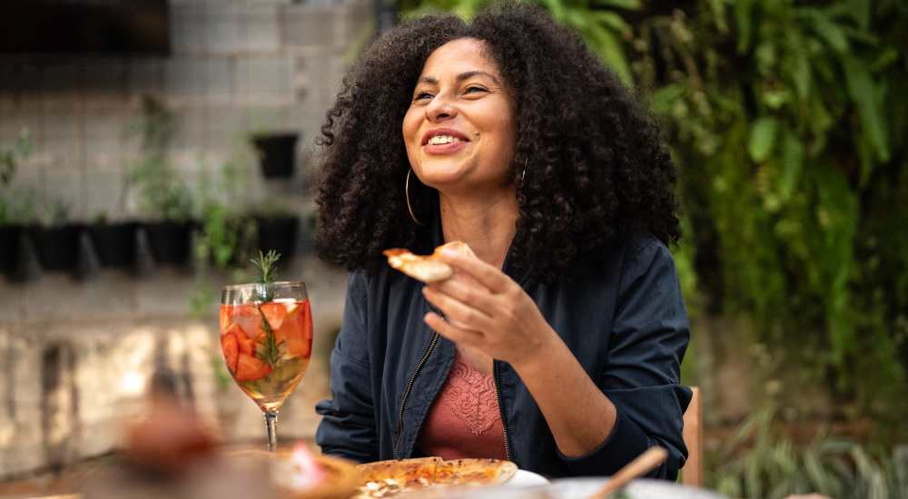Woman enjoying meal on outdoor patio at The Larsen Apartments in Dallas, Texas 