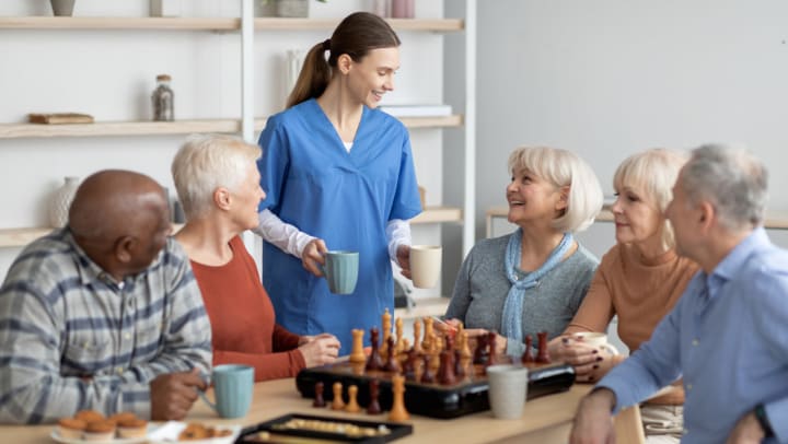 A group of seniors and a caregiver chatting
