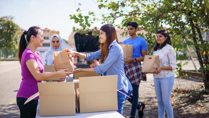 a group of volunteers with boxes filled with paper bags of food on a table | volunteering in Katy