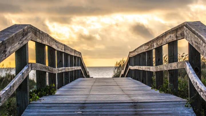 A boardwalk leading to the beach at sunset.