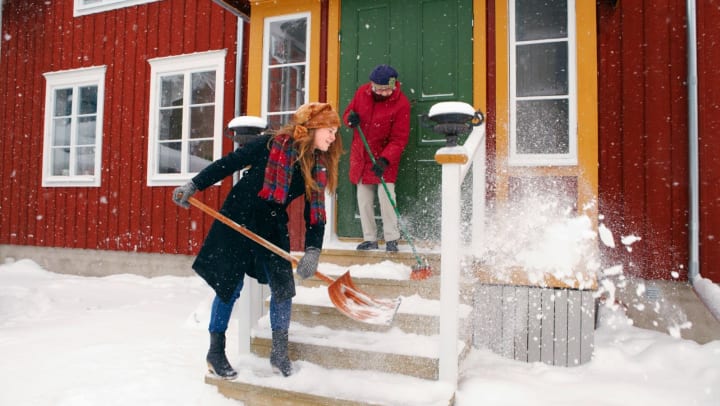 Young woman helping older lady shovel snow