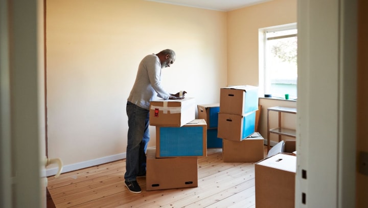 Older man packing boxes in empty room
