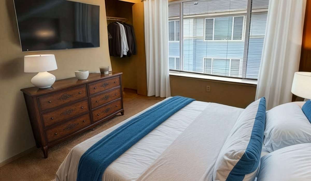Bedroom with a neatly made bed with a wall-mounted TV at Ivy Ridge Apartments in Seattle, Washington