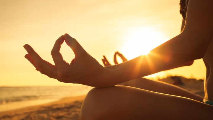 Woman sitting on the beach meditating during sunset near Odyssey Lake Apartments