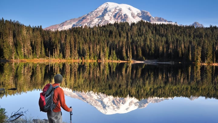 Man standing in front a lake with a snowy mountain peak in the distance