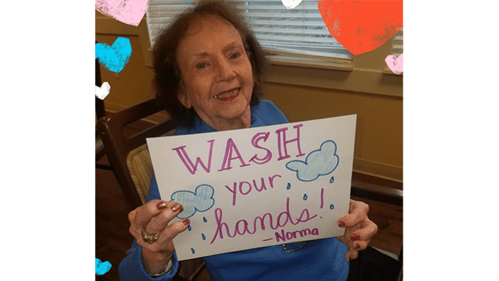 Harvester Place resident holding "wash your hands" sign