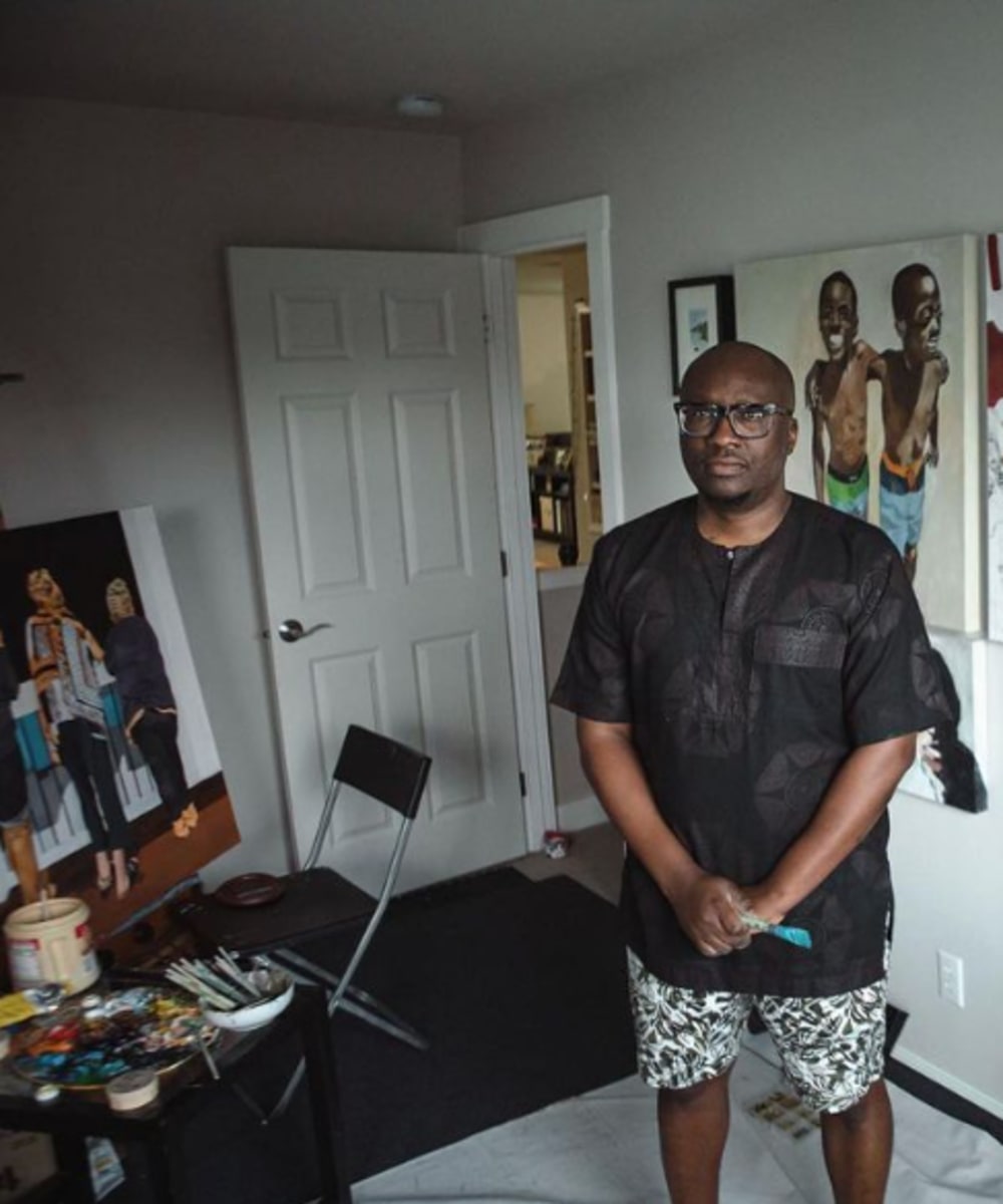 Dimeji Onafuwa in his art studio surrounded by painting supplies and his art.