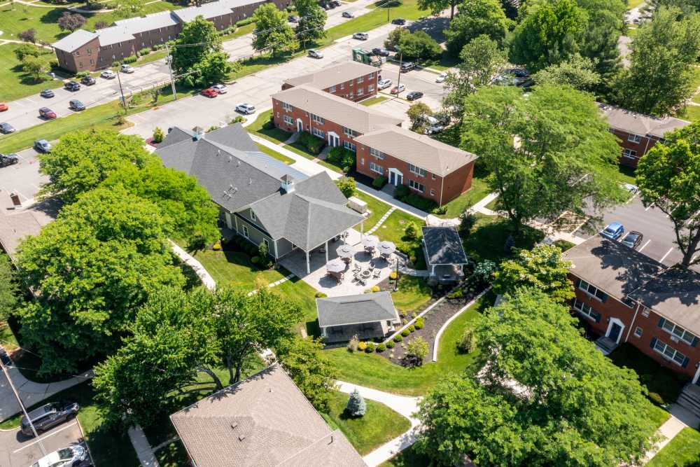 Aerial view of a residential community with brick apartment buildings, landscaped courtyard, walking paths, and surrounding trees at Center Grove Village in Randolph, New Jersey.