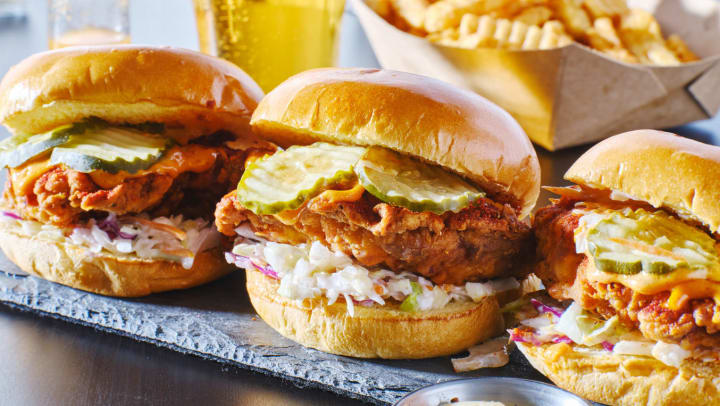 Three chicken sandwiches lined up, all topped with pickles and cole slaw