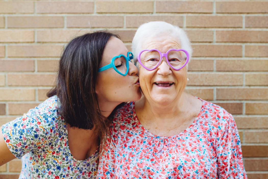 Daughter kissing senior mother at Iris Memory Care in Edmond