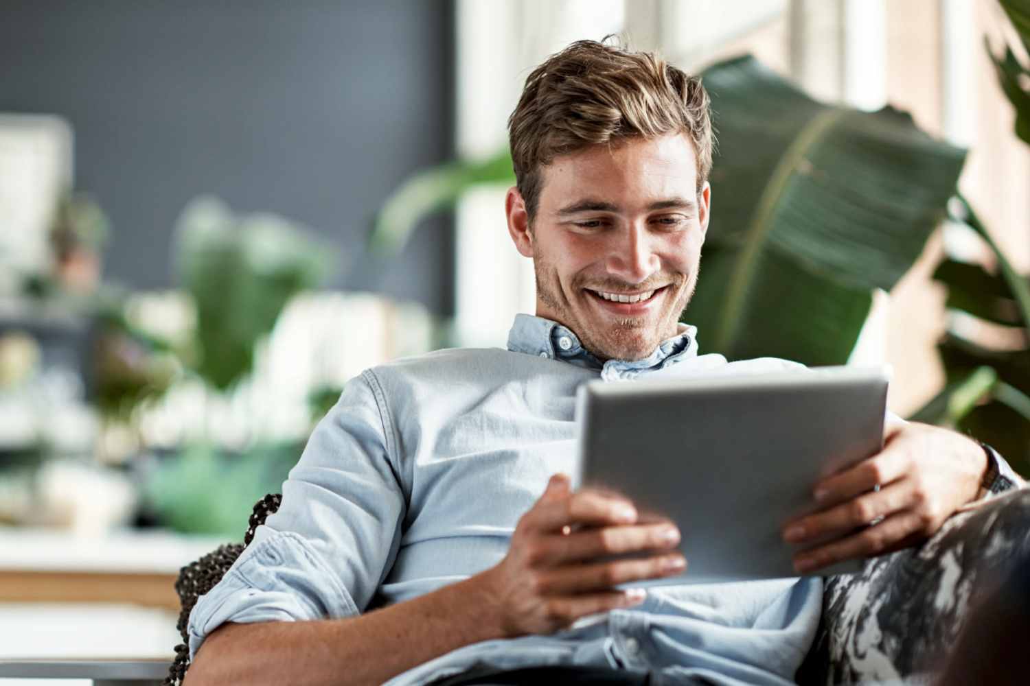 Resident relaxing on the couch with an iPad in the living room at Southwood Apartments in Shepherd, Texas