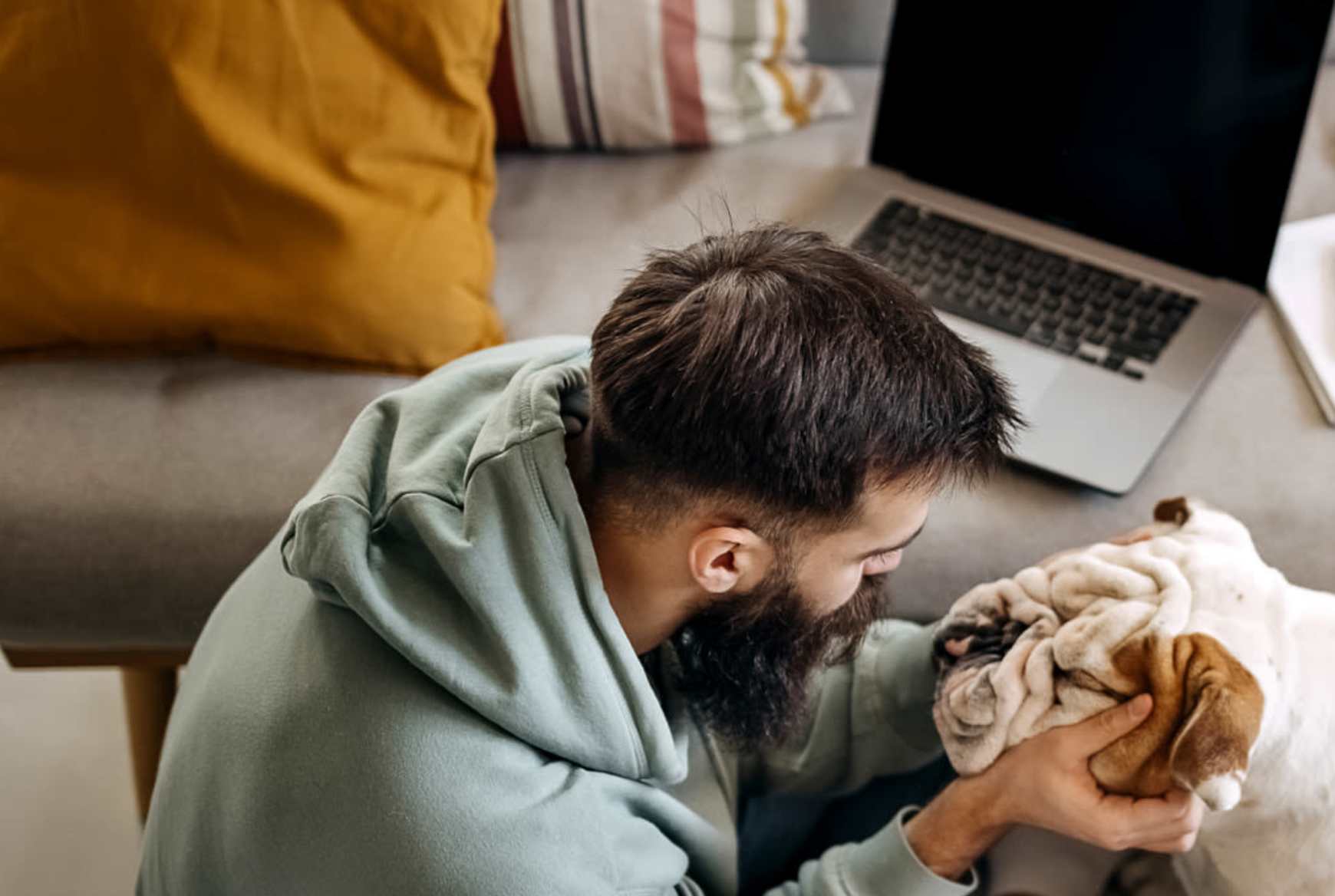 Resident playing with his puppy on hardwood floor in living room at the pet-friendly at Flatiron District at Austin Ranch in The Colony, Texas