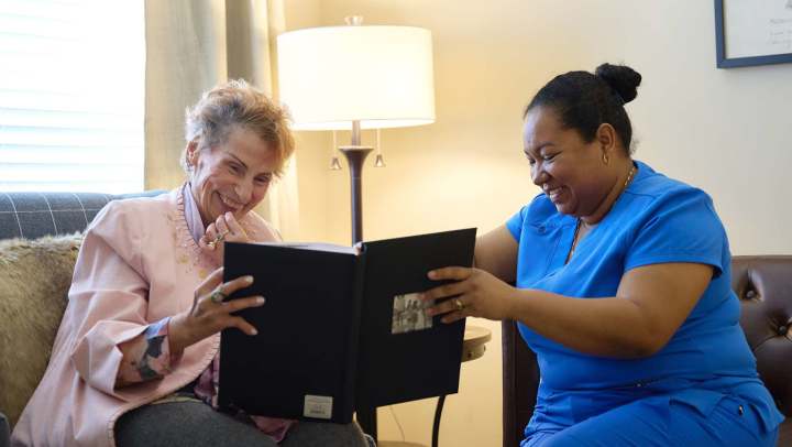 Harmony Senior Living resident enjoying a photo album with a caregiver