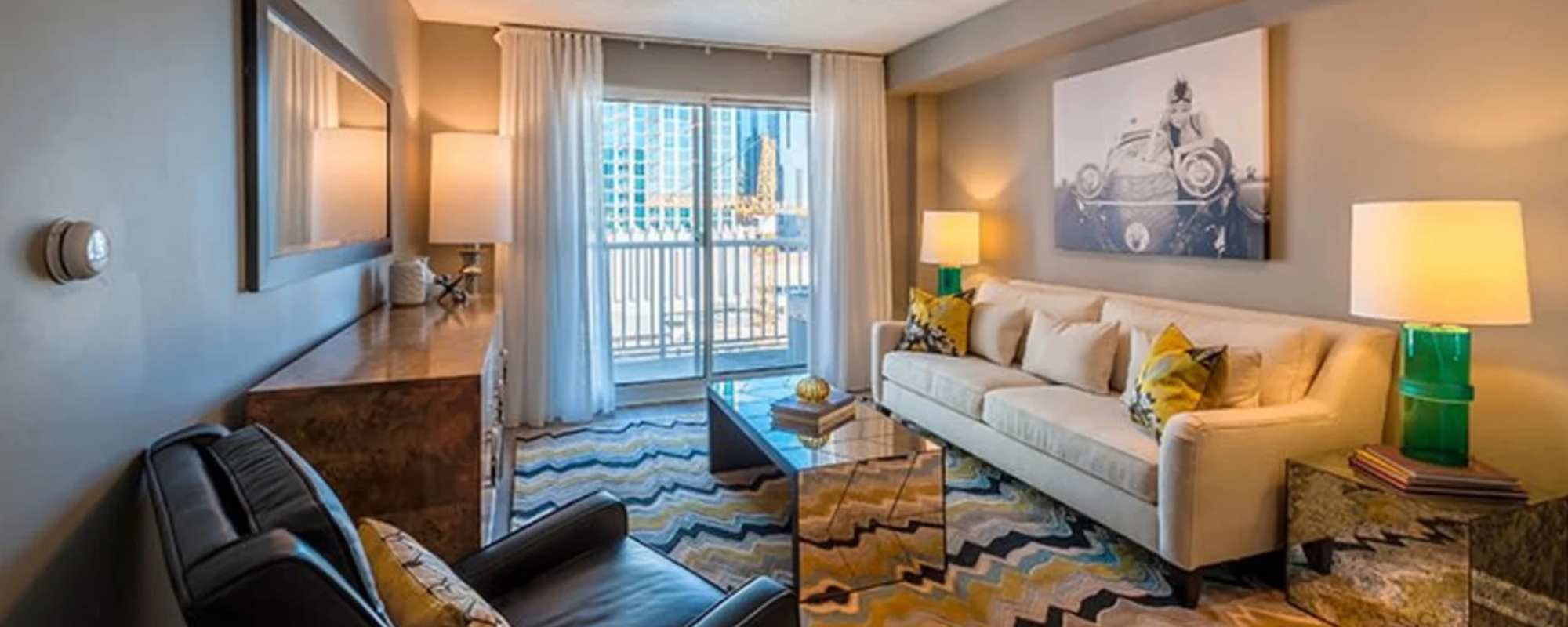 Downtown Nashville, TN, Apartments Near Capitol View Nashville - Cumberland on Church - Living Room With Couch, Coffee Table, Armchair, Wall Art, Side Tables, Lamps, and Glass Doors.