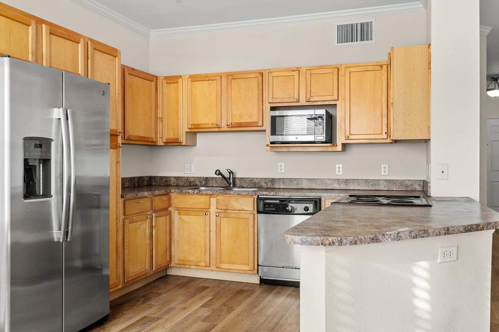 Kitchen with wood-style cabinetry, large breakfast bar, and stainless steel appliances at Briargate on Main in Parker, Colorado