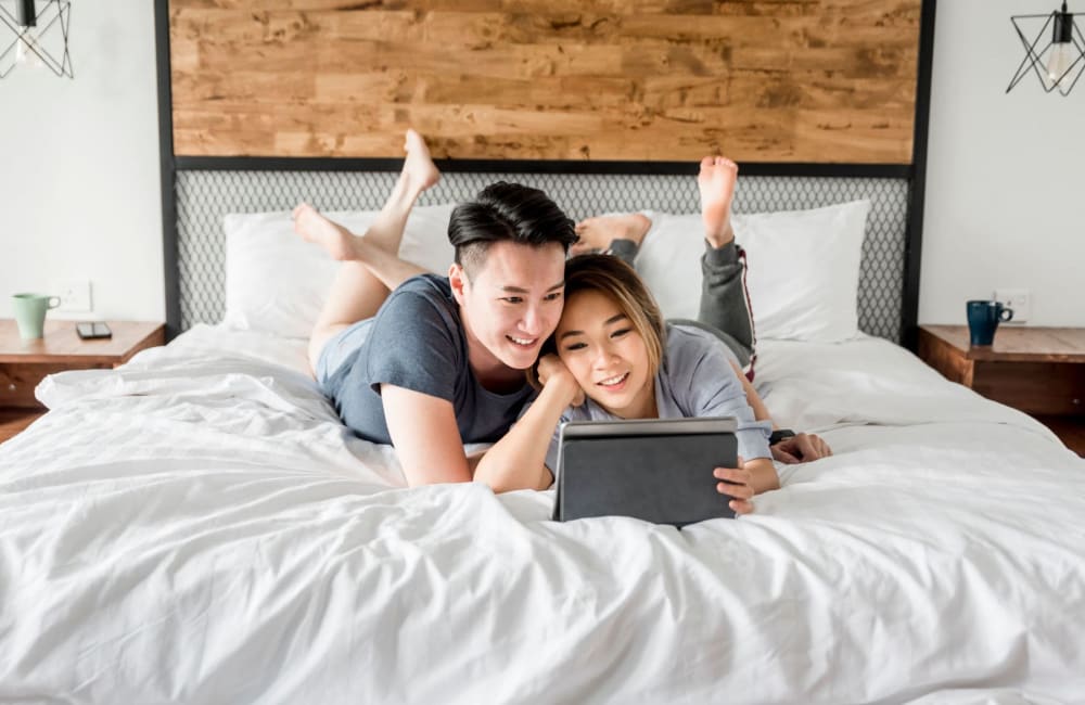 Couple relaxing on a bed at Affordable Apartments at Vasco Station in Livermore, California