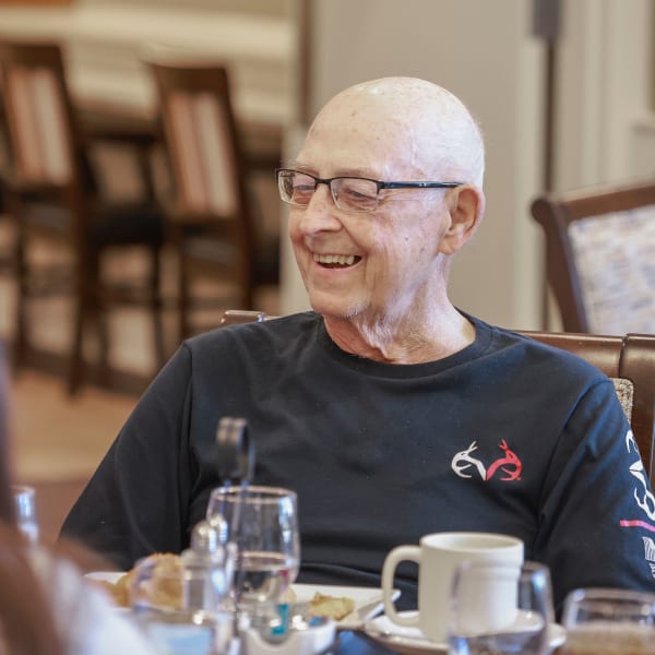Two residents laughing while talking over coffee at The Princeton Senior Living in Lee's Summit, Missouri