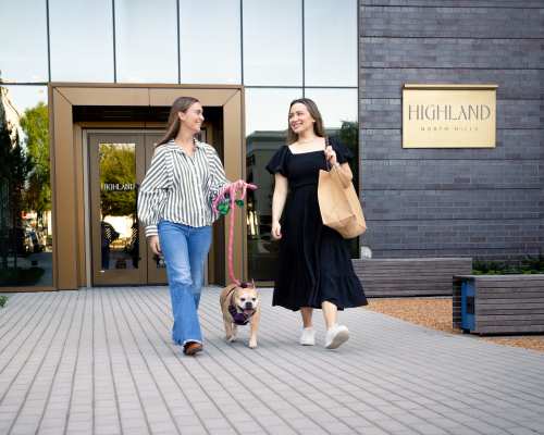 Two women walking outside talking with a dog at Highland North Hills in Raleigh, North Carolina