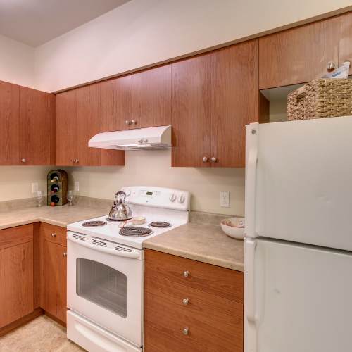 Modern kitchen with wooden cabinets and refrigerator at Avion Apartments in SeaTac, Washington