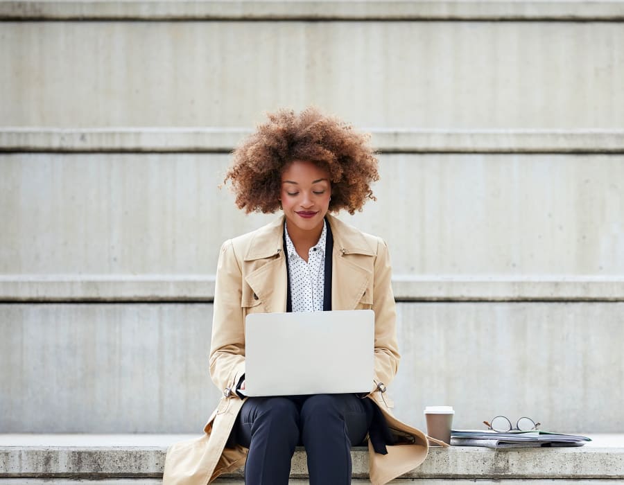 Resident working on her laptop on the steps outside her office near Verse Seattle in Seattle, Washington