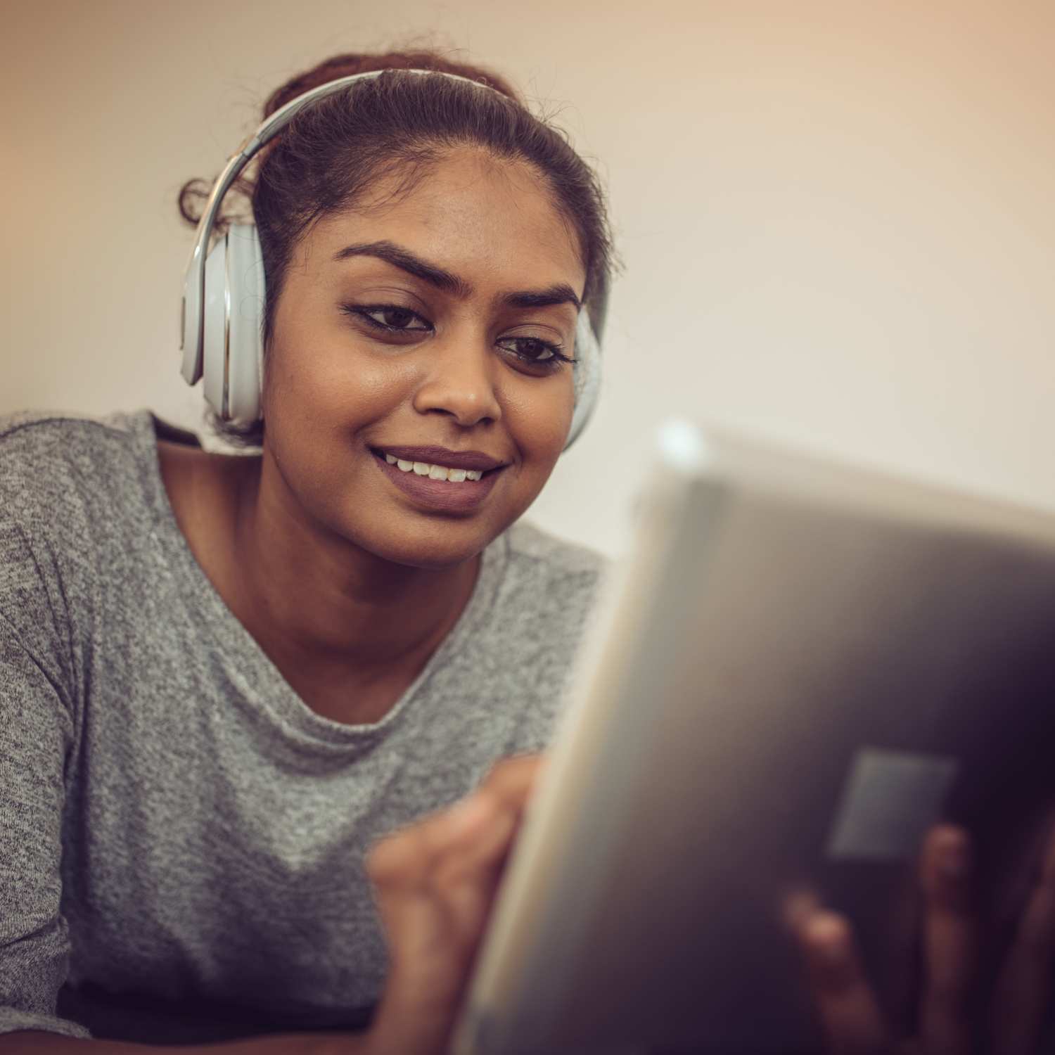 Woman using her tab with headphones at Reeds Landing Apartments in Edmond, Oklahoma  