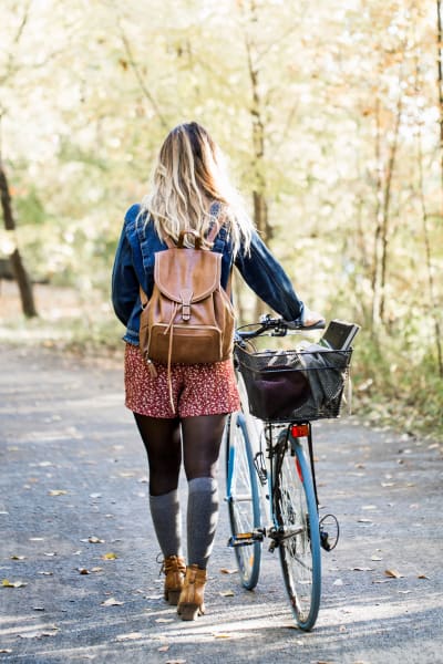 Resident walking her bike down a beautiful tree-lined street near The Alcott in Denver, Colorado