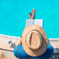 A man sitting on the edge of the pool reading at The Courts of Avalon in Pikesville, Maryland