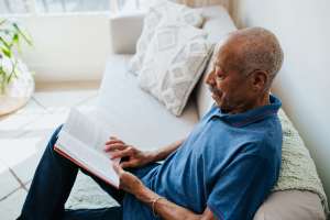 An old man reading books in a living room at Traditions at Federal Way in Federal Way, Washington