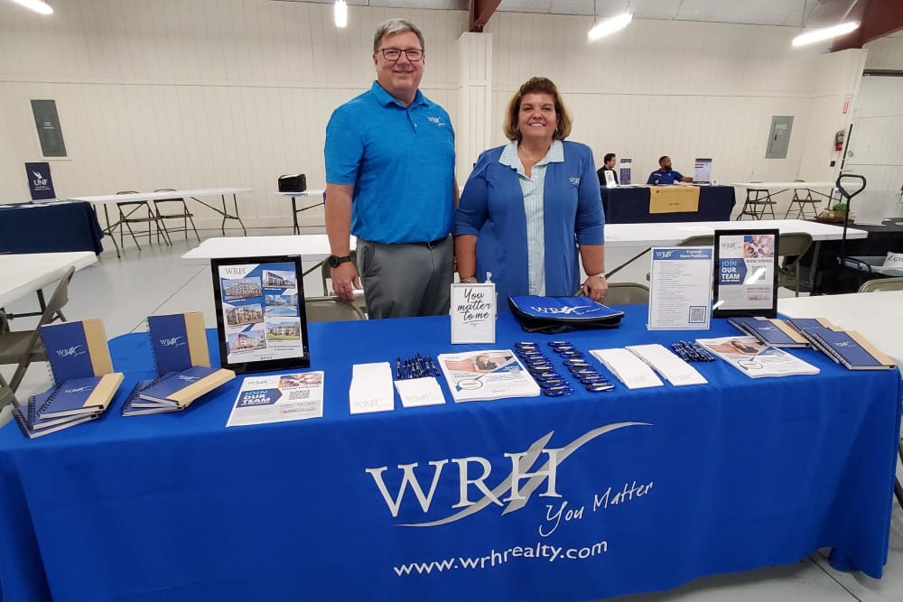 Employees of at WRH Realty Services, Inc work a booth at a local charity event
