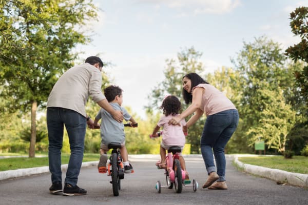 Parents helping the kids ride bikes at a park near Canyon Grove in Grand Prairie, Texas