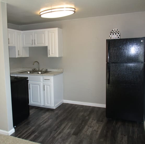 Modern kitchen with black appliances and faux hardwood floor at Lamar Station Apartments in Lakewood