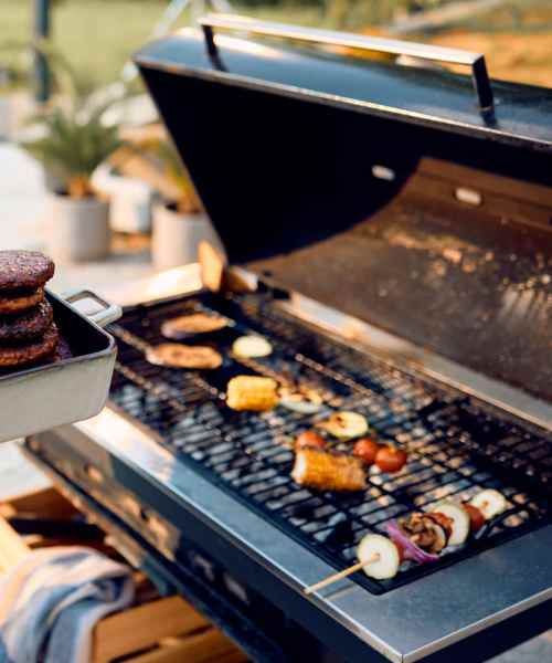 Grilling burgers and vegetables on a modern barbecue in a sunny outdoor space at Arlington Greene in London, Kentucky