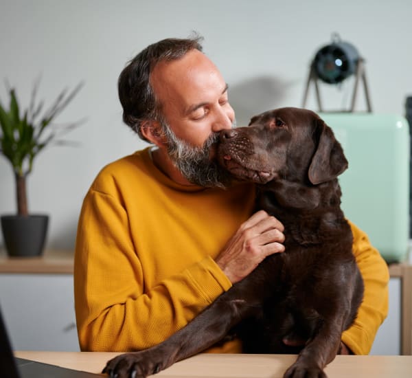 A man hugging his dog in his apartment at Cypress McKinney Falls in Austin, Texas