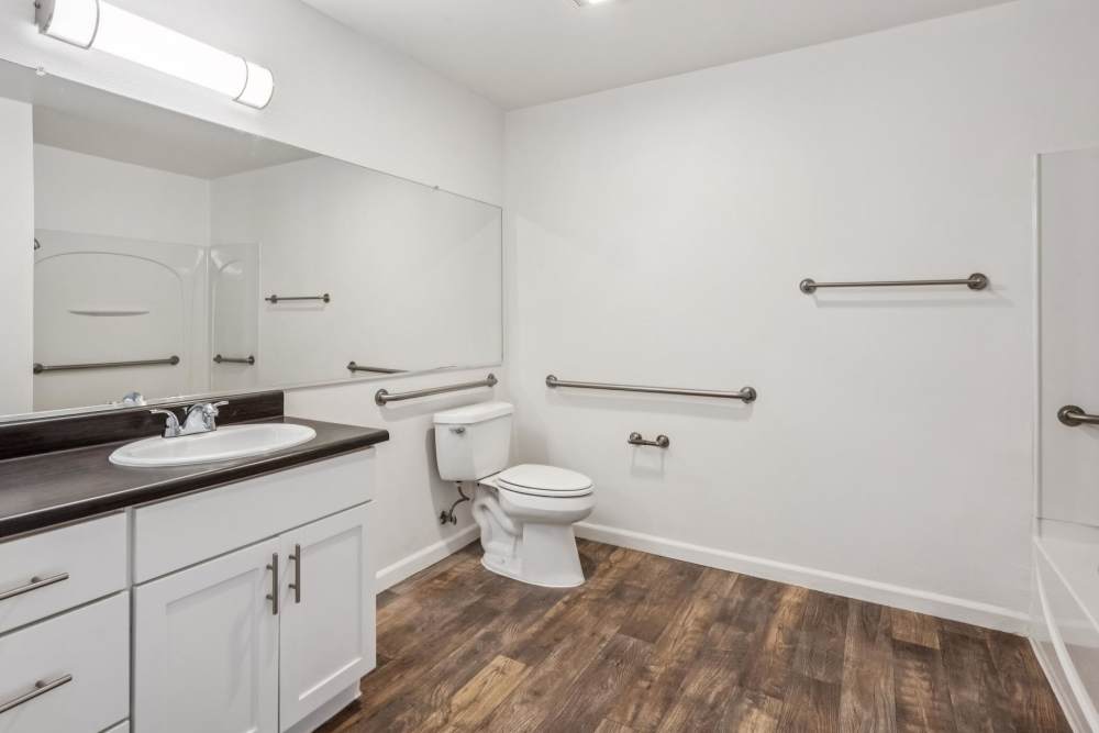 Very large bathroom with white cabinets, dark counters, and wood-style flooring at Azure Apartment Homes in Petaluma, California