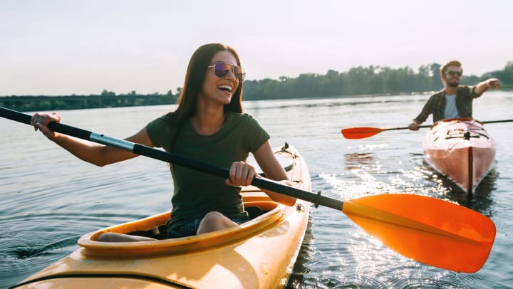  Woman and a man in kayaks on the water, pointing at something with smiles on their face. 