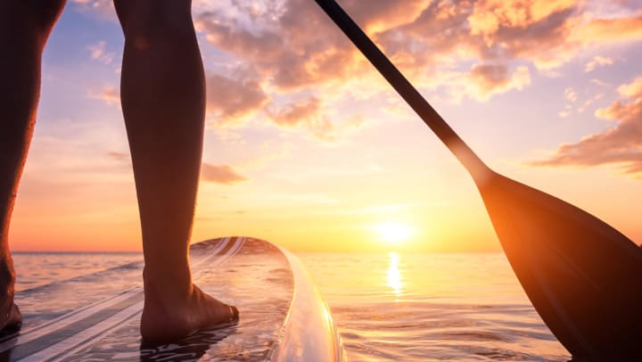  Close-up of stand up paddleboarding on a quiet sea at sunset. 