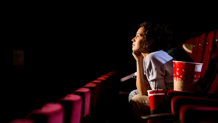 Young woman watching a movie in an empty movie theater