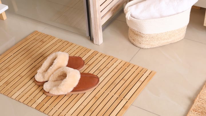 bamboo bath mat with slippers on bathroom floor | details to transform bathroom