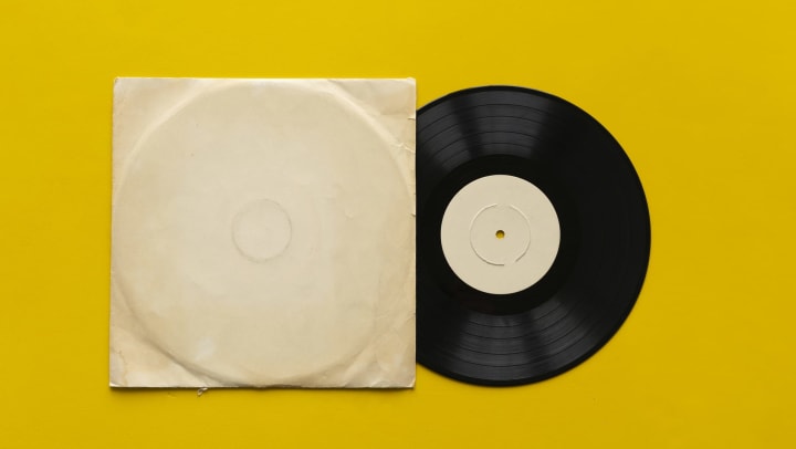 Vinyl record partially in sleeve against a yellow background