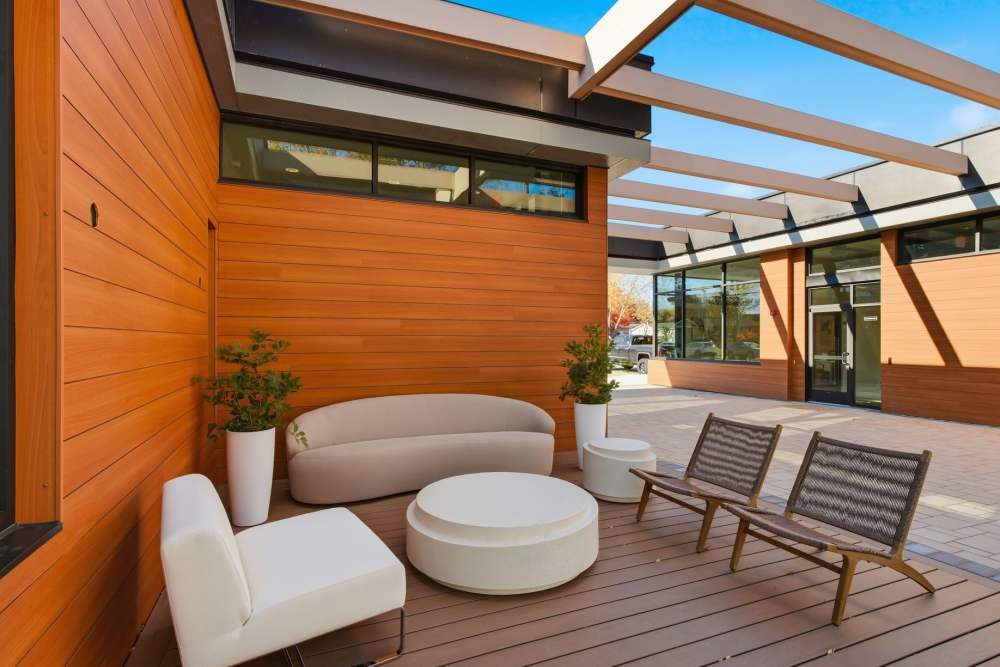 Resort-style swimming pool with lounge chairs and orange umbrellas, coming soon at Eagle Rock Apartments at Woodbury in Woodbury, New York