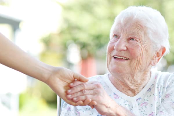 A resident of Ramsey Village Continuing Care holding her caregiver's hand in Des Moines, Iowa